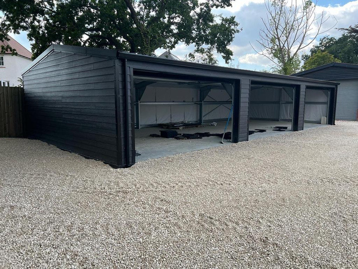 A dark-clad Bentley build with open bays on a gravel site